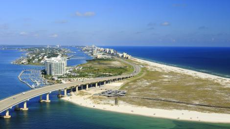 Carretera que cruza sobre el agua y junto a playas de arena blanca en Gulf Shores, Alabama