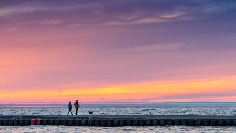 Couple walking along a pier at sunset in Grand Haven, Michigan