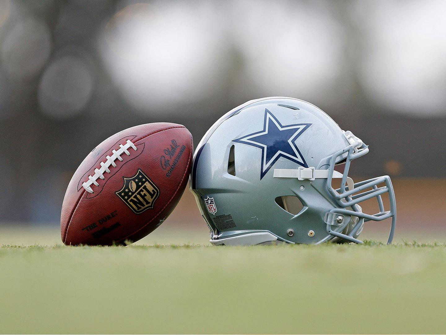 Uma bola de futebol americano e um capacete do Dallas Cowboys no centro de treinamento em Oxnard, Califórnia