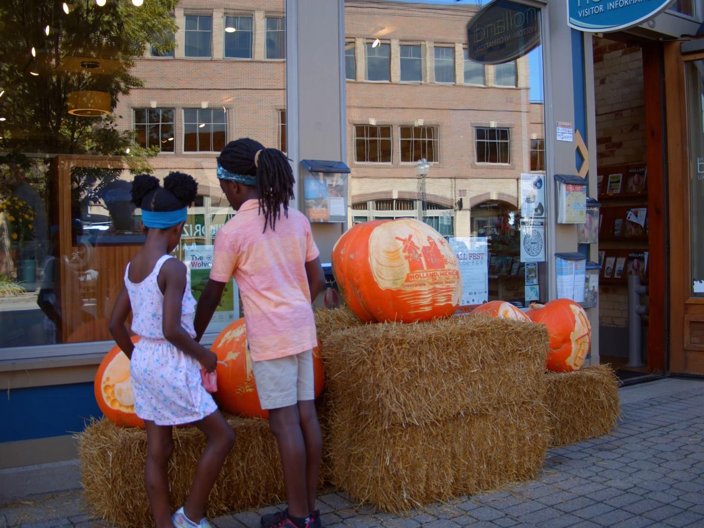 Kinder beim Betrachten von ausgehöhlten Kürbissen während des Fall Fest im Stadtzentrum von Holland, Michigan