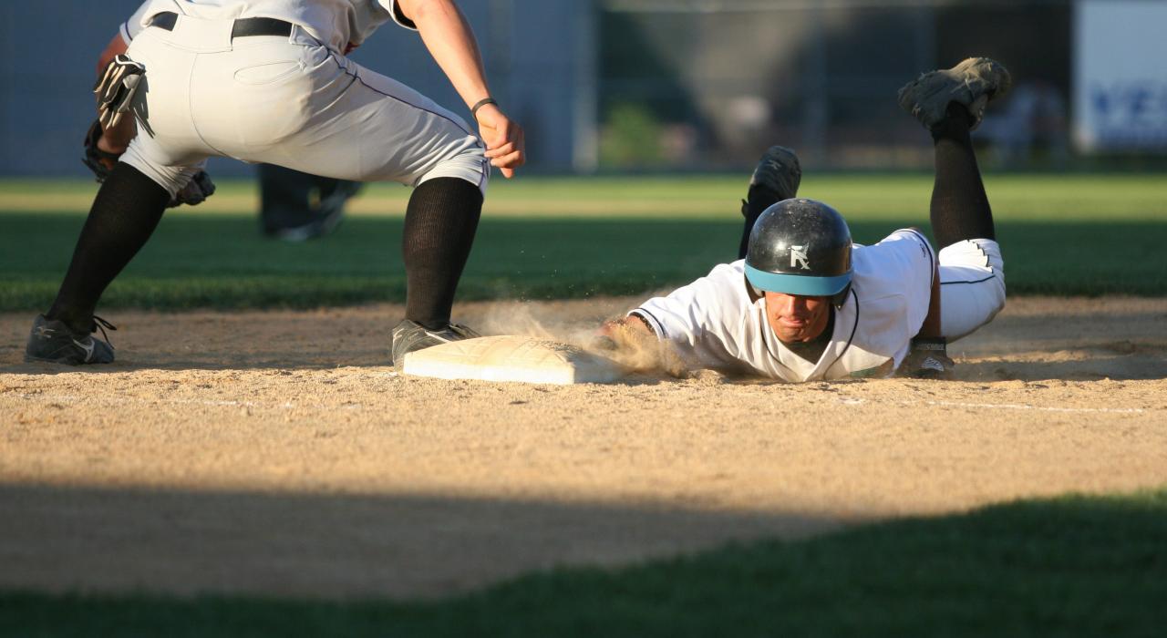 Deslizándose a una base en un partido de béisbol de los Rochester Honkers