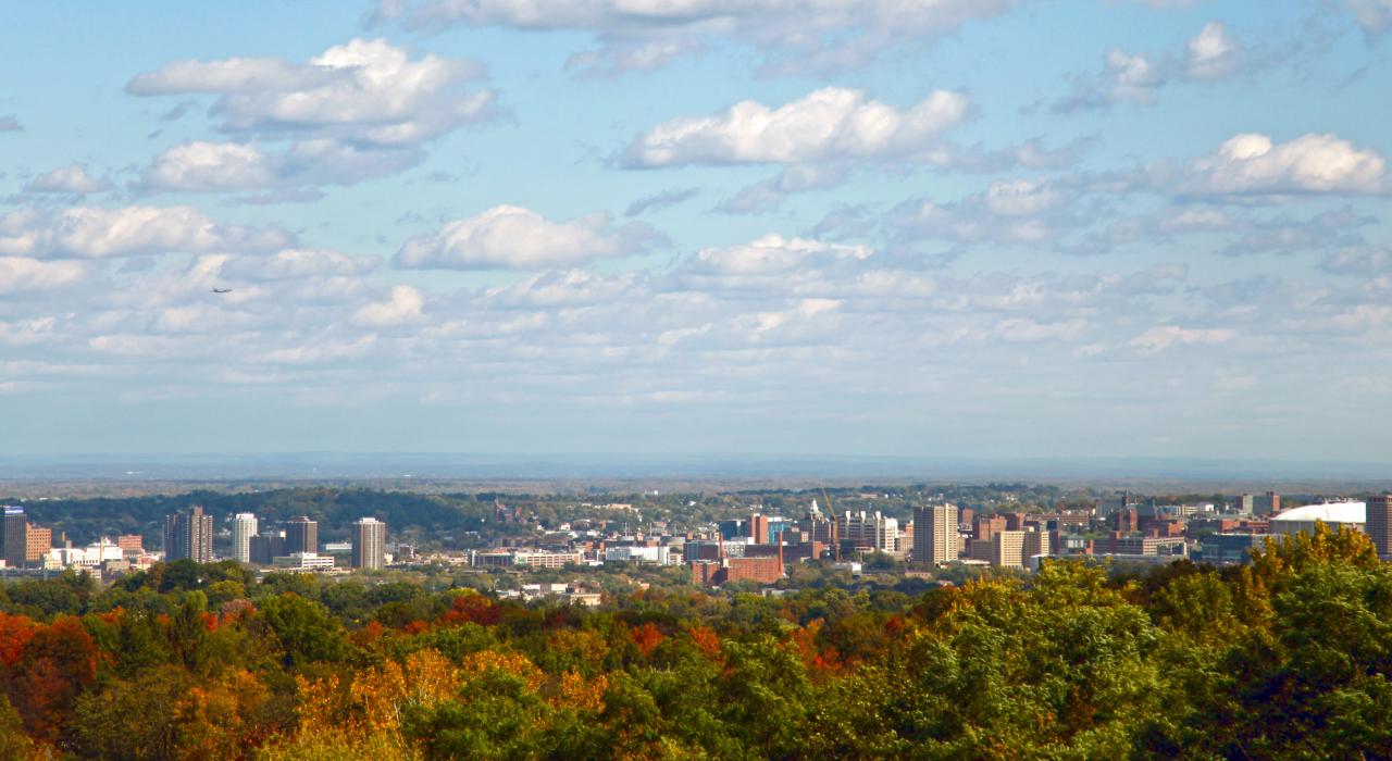 Folhas de outono e nuvens leves emolduram o horizonte da cidade