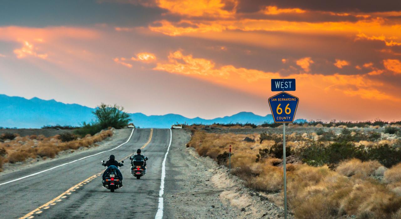 Motorcycles cruising through the California desert on Route 66 at sunset