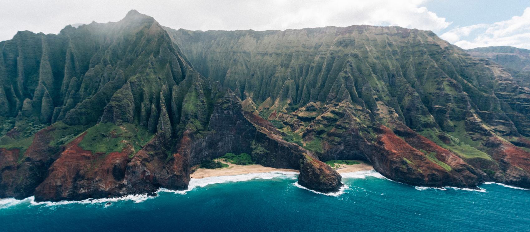 Towering sea cliffs meet the Pacific Ocean at Nāpali Coast State Wilderness Park on Kauaʻi