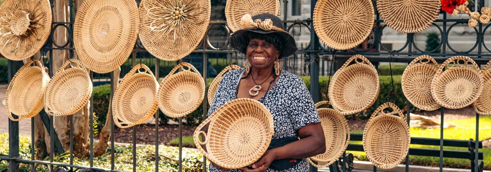 A Gullah artisan posing with one of her sweetgrass baskets in Charleston, South Carolina A Gullah artisan posing with one of her sweetgrass baskets in Charleston, South Carolina